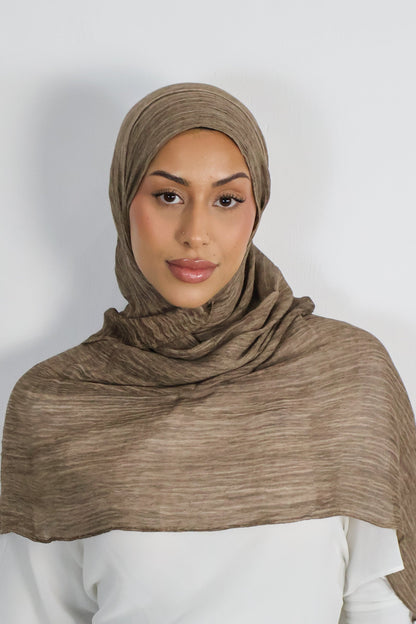 Woman wearing a brown hijab against a white background