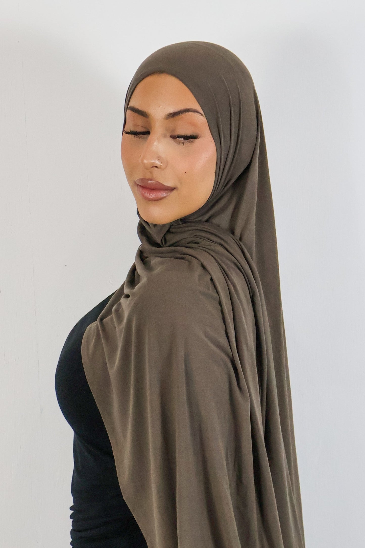 Woman wearing a brown hijab against a white background