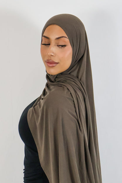 Woman wearing a brown hijab against a white background