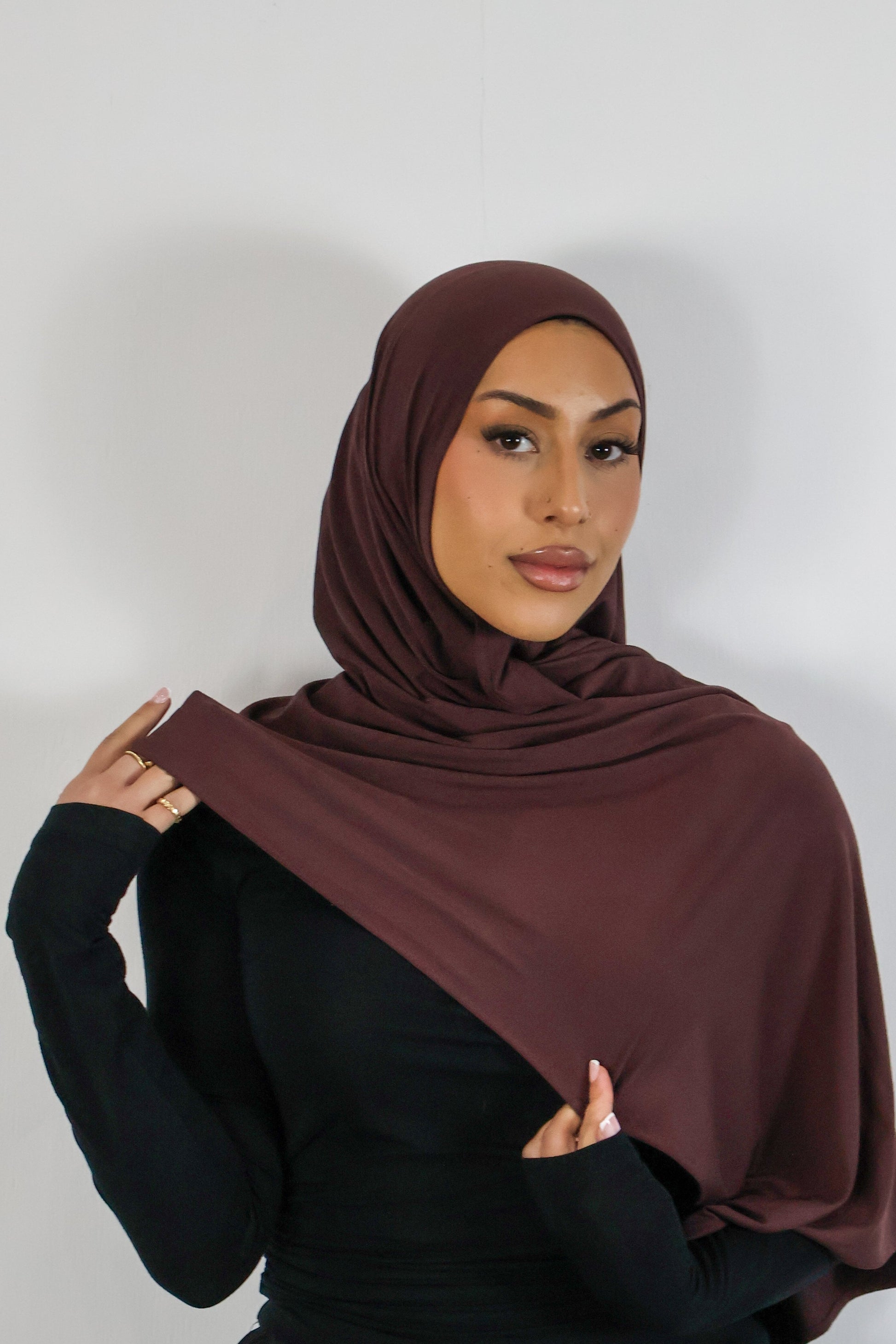 Woman wearing a deep plum hijab against a white background